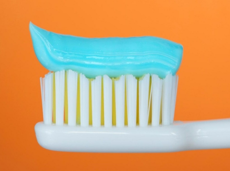hjemmemedicin-tandpine-tandpasta-blå-tandbørste-hvid-orange