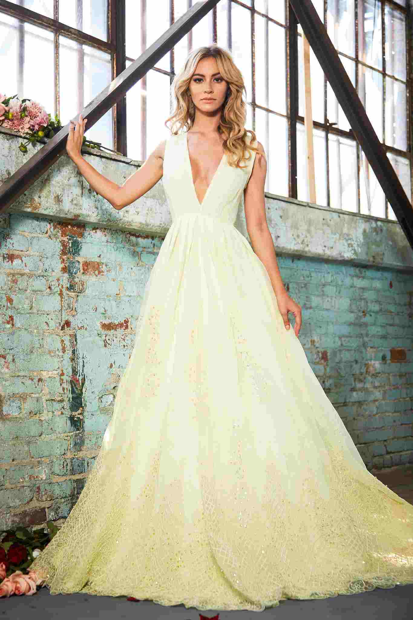 Lysegul kjole til brylluppet med en dyb halsudskæring, blonde og glitrende pailletter