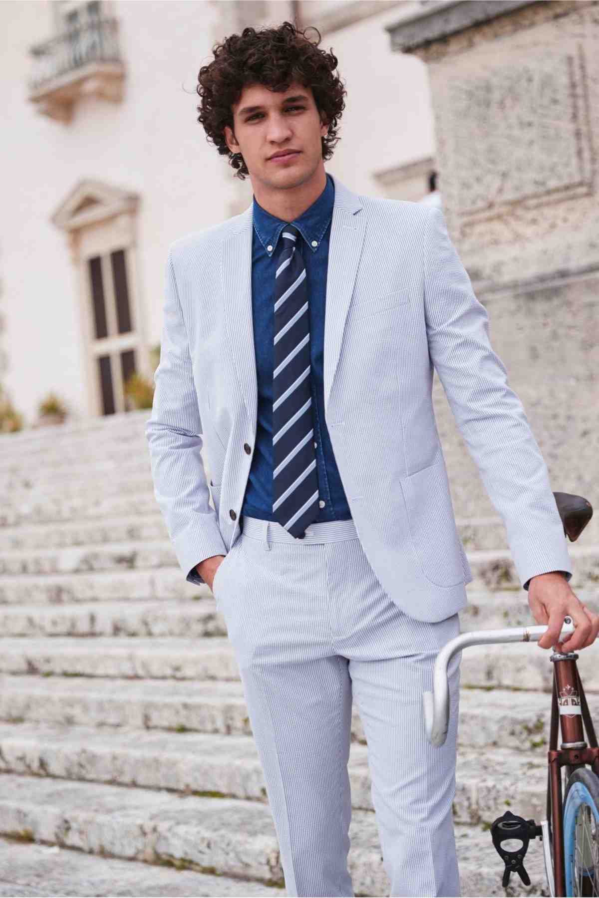 seersucker -jakkesæt i lysegrå med slips og denimskjorte til et sommerligt look