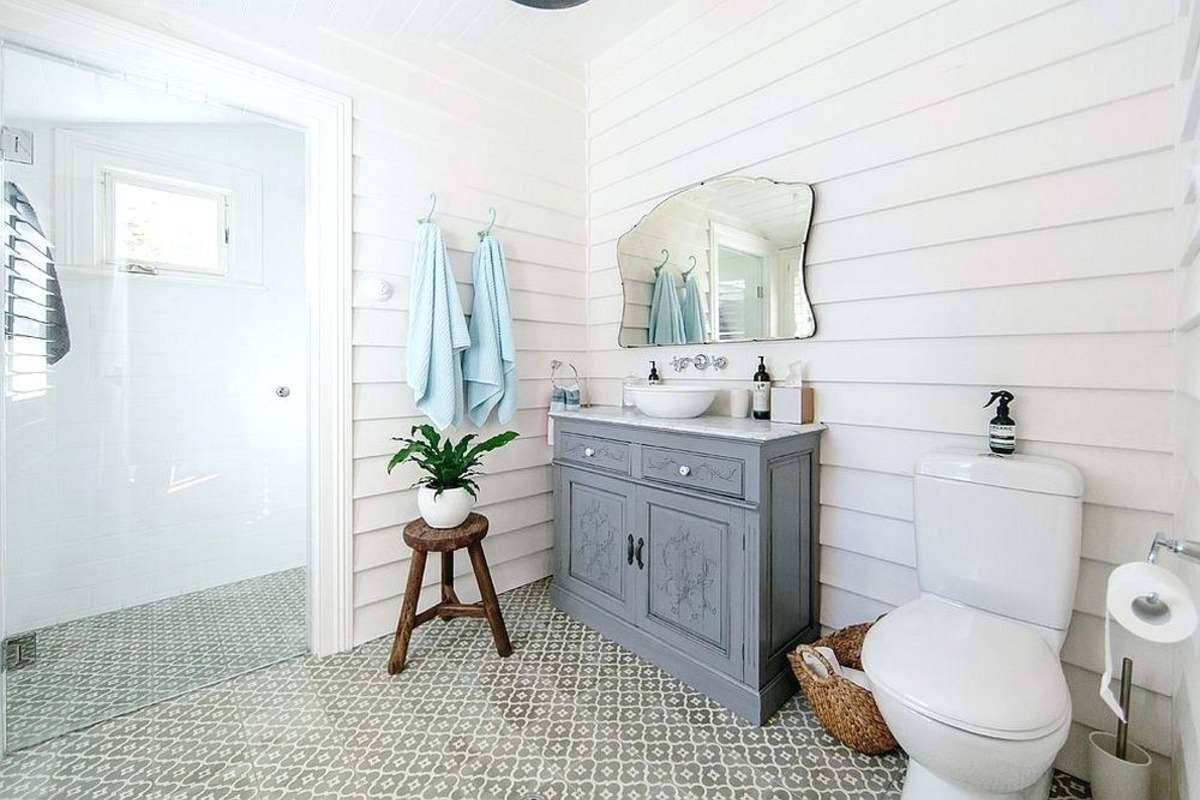 rummeligt badeværelse i landlig stil med grå vaskeskab og moderne brusebad