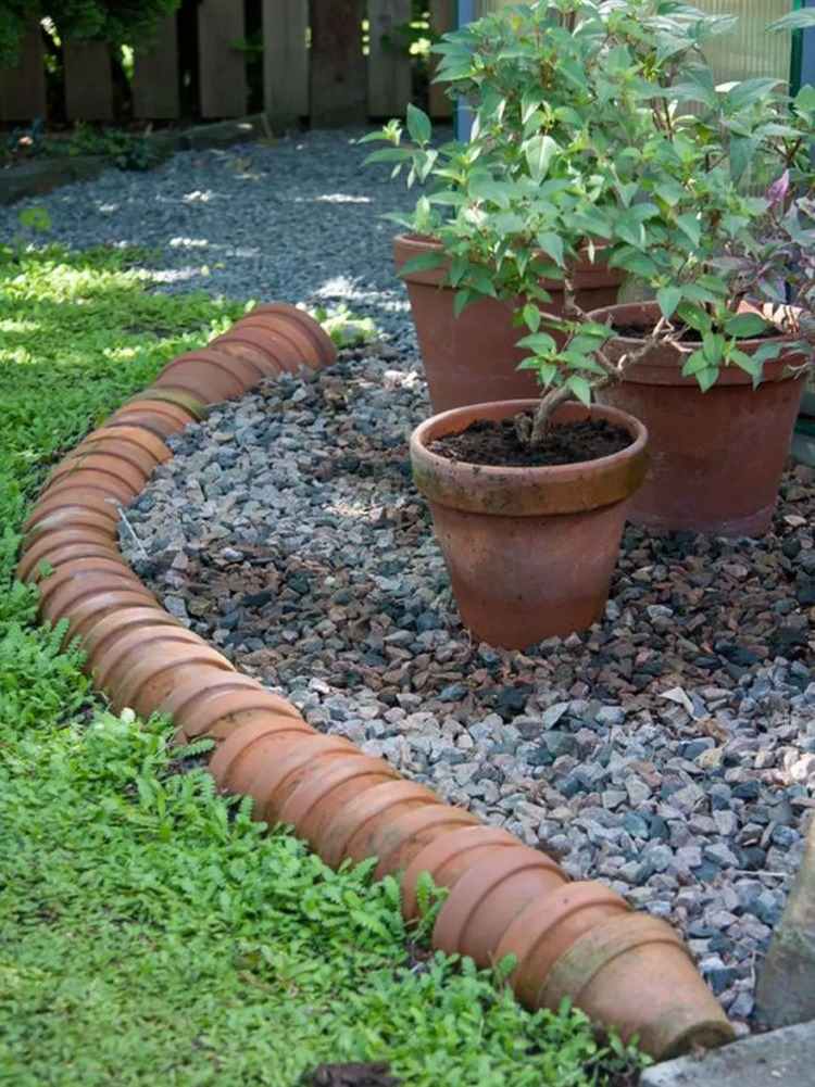 gamle urtepotter placeret den ene inden i den anden som en kant i haven