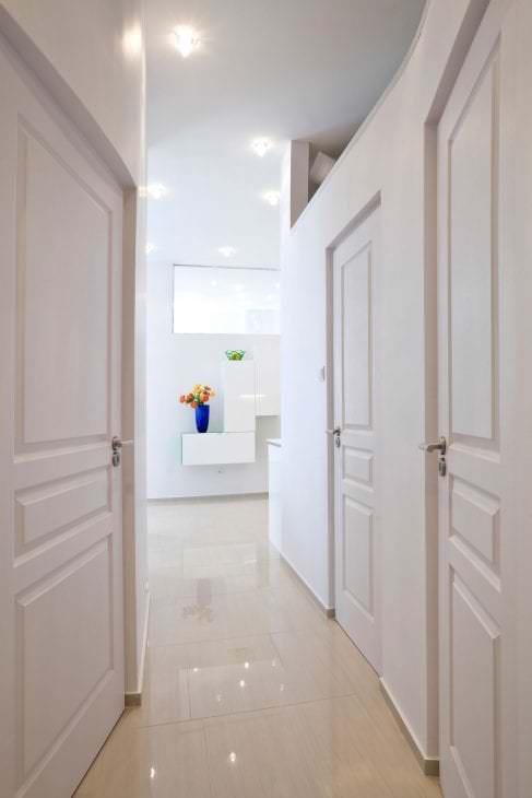 Fehér ajtók a folyosón, fényes padlóval