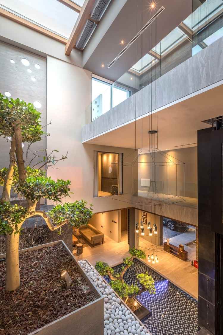 højt til loftet og bonsai -træ i kombination med lysekrone med biofilt design