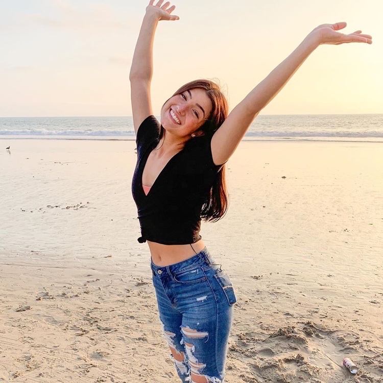 Charli D'Amelio med en croptop og jeans med høj talje på stranden
