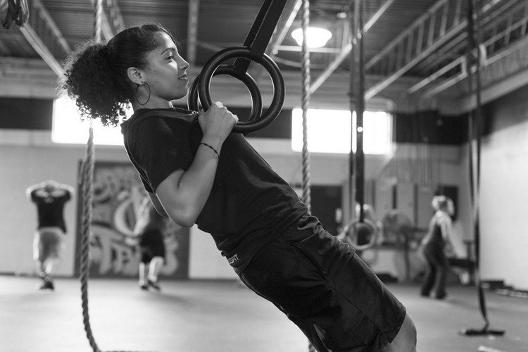 kvinde træner med ringe i gymnastiksalen med udstyr og sportstøj