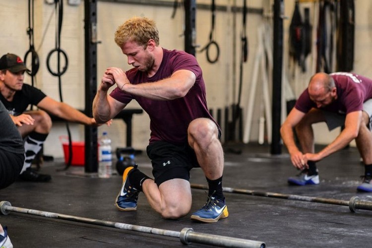 crossfit træner viser gruppens øvelser med benene i gymnastiksalen