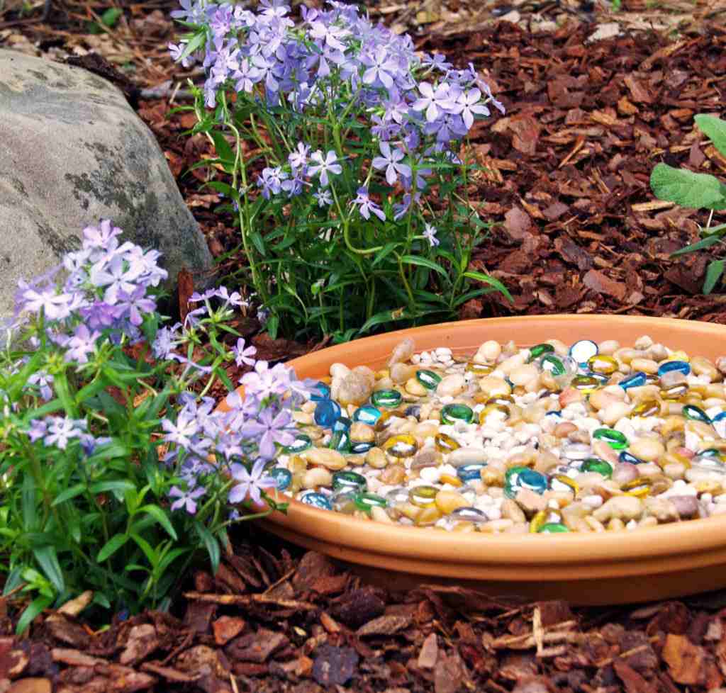 Terracotta -tallerken fyldt med farverige glassten som bi -drikker og dekoration til haven
