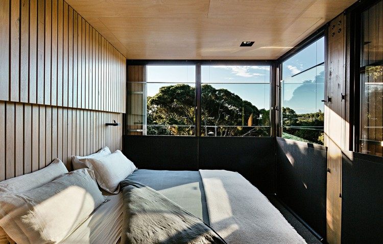 design sommerhus skråtag kystskov moderne bjerghytte soveværelse seng vindue udsigt sollys