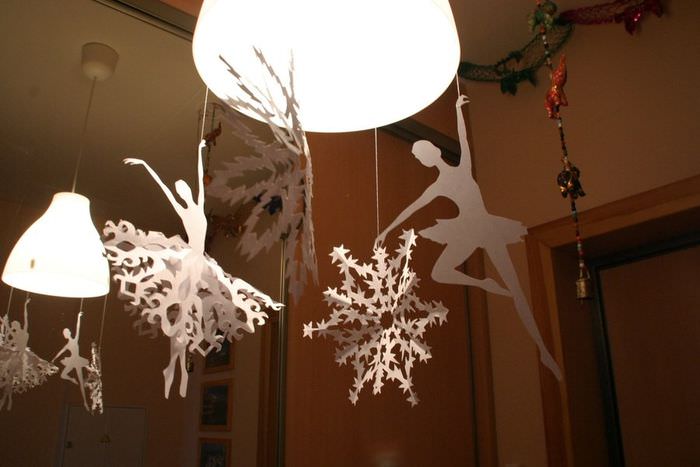 Коледни хартиени снежинки върху лампата на хола