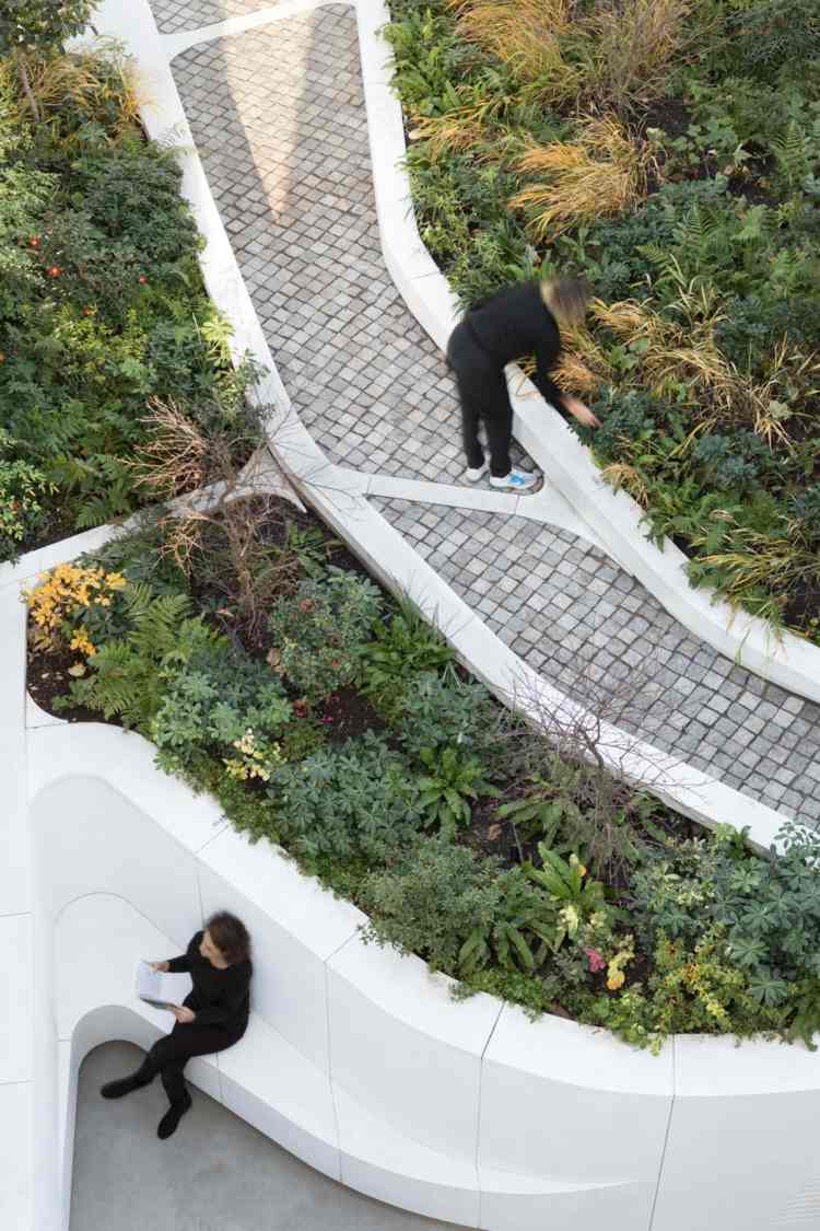 Frodige blomsterbed i en byhave og designet med hvid beton