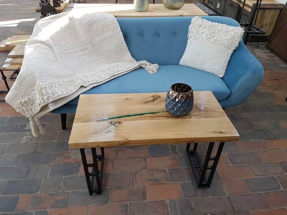 lyseblå sofa med tæppe og hynder bag sofabord lavet af træ og epoxy