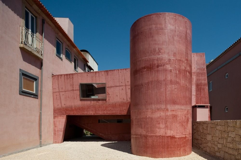 husforlængelse og passage lavet af røde konstruktionselementer, beton, pigmenteret og indsat