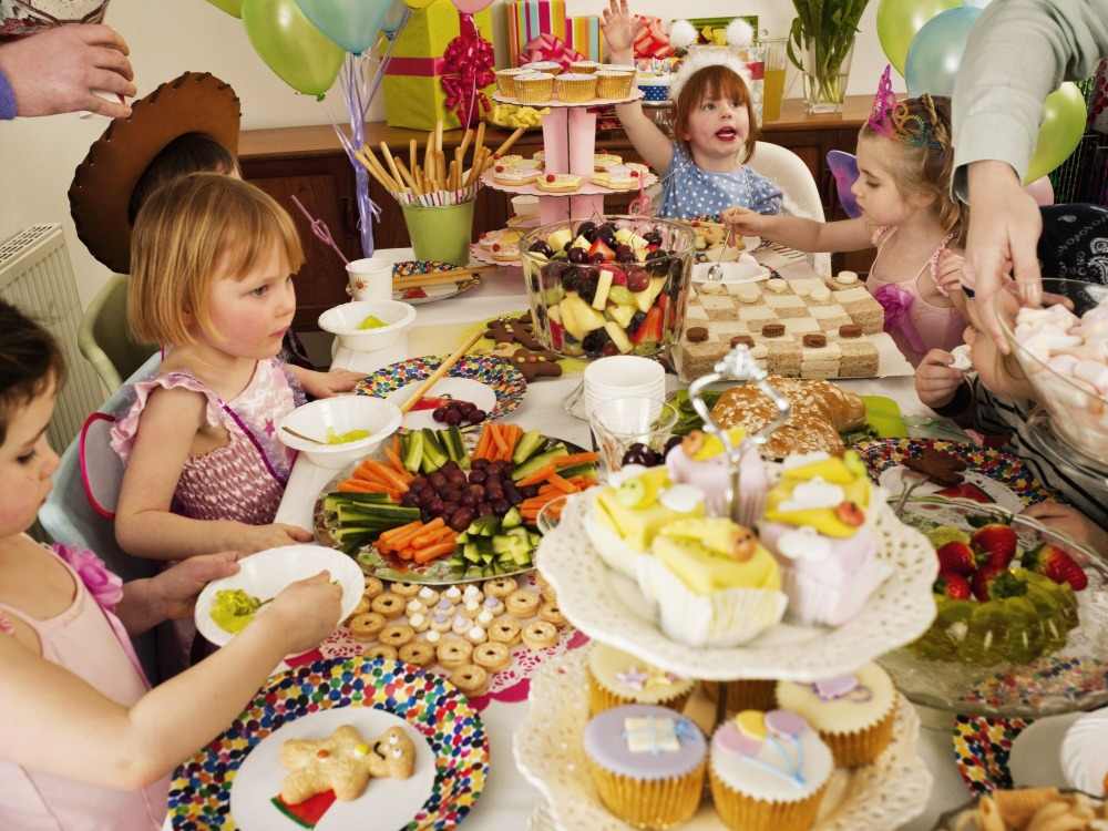 børn fejrer deres fødselsdag med et fuldt bord med omhyggeligt tilberedte delikatesser