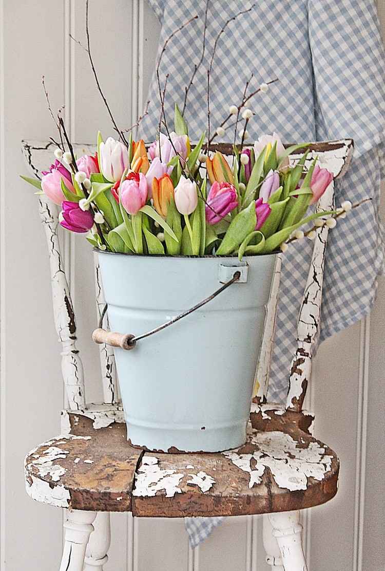 Vintage forårsdekoration til udendørs. Metalspand med tulipaner på en gammel stol