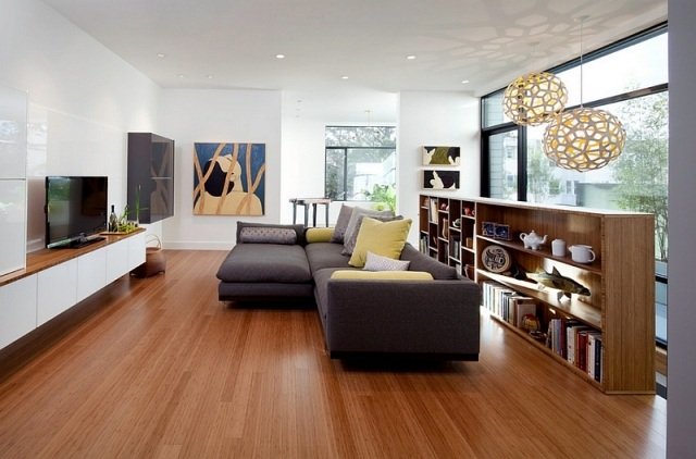 stue-åbent-design-træ-gulv-hylde-rumdeler-grå-hjørne-sofa-gul-dekorative puder