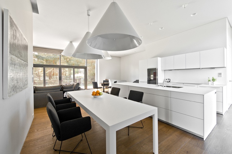 hvidt køkken med køkkenø spisebord grå polstret lænestol XXL hængelamper