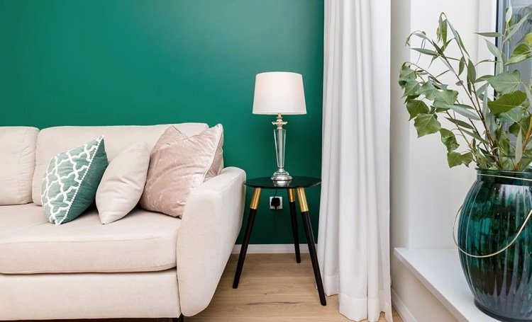 smaragdgrøn væg bag sofaen i creme