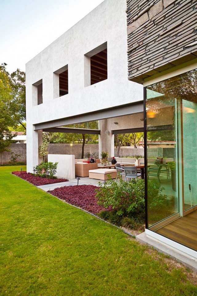 Moderne villa glas foran møbleret terrasse græsplæne landskabsdesign