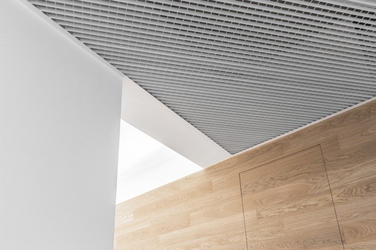 Trægulv og hvide gipsvægge og loft med integreret ventilationssystem eksempel på moderne indretning