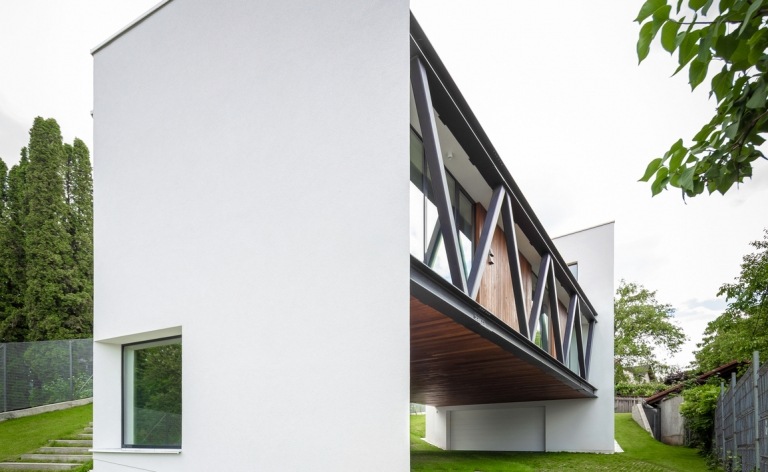 Hus på en bjergskråning med en pudset hvid facade med store vinduer og træelementer