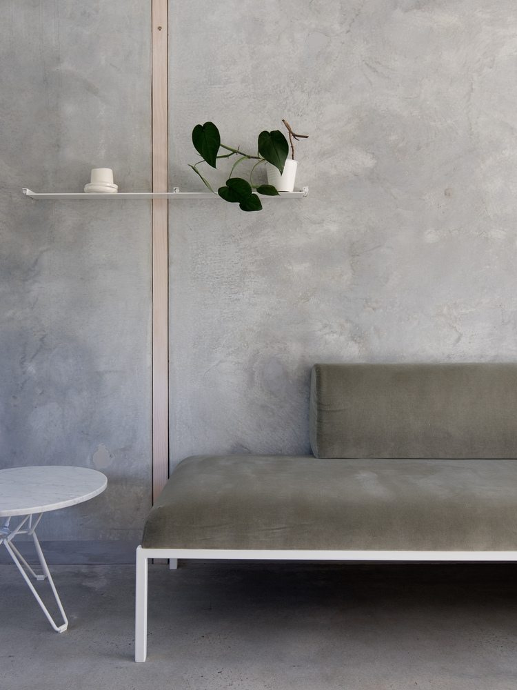 grå vægge af beton i kombination med en subtil sofa og sidebord af marmor