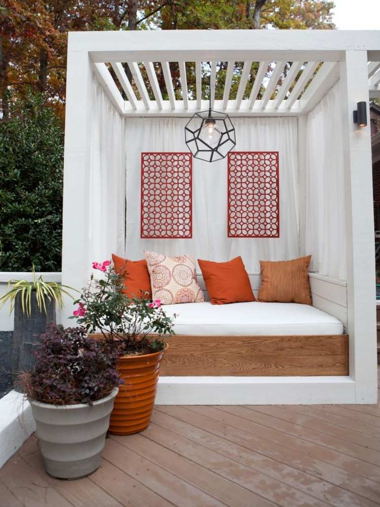 træ-pergola-gardiner-træ-konstruktion-hvid-daybed-pude-planter-orange-planter-blomster