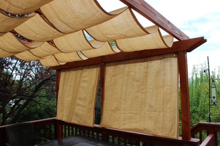 træ-pergola-gardiner-stof-luftig-beige-solbeskyttelse-træ-konstruktion-gelænder-have-skygge