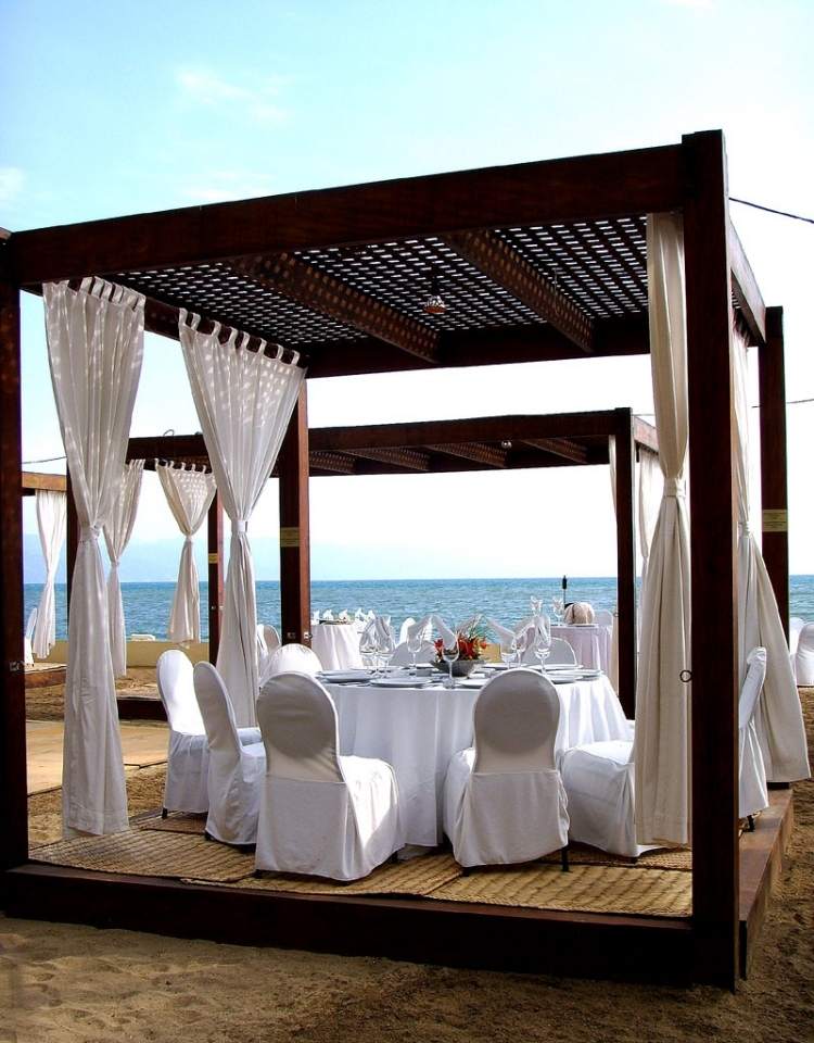 Træpergola -gardiner-strand-bryllup-hvid-stol-betræk-hav-romantisk-sand
