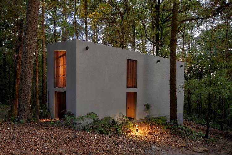 Udvendig facade af et sommerhus i skoven lavet af vulkansk sten og bæredygtige materialer
