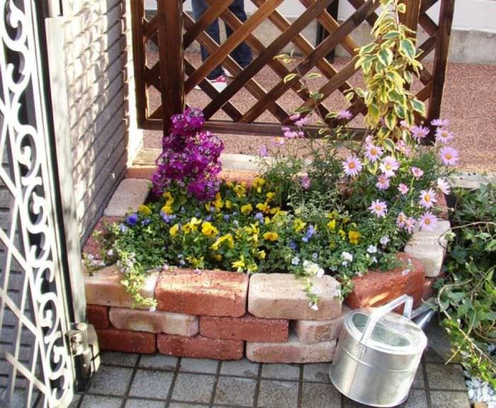 Tegel blomsterrabatt framför porten och vattenkanna