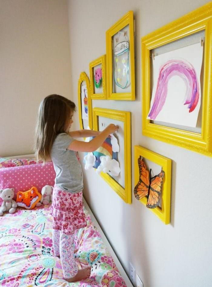 Момичето украсява стаята със собствени рисунки