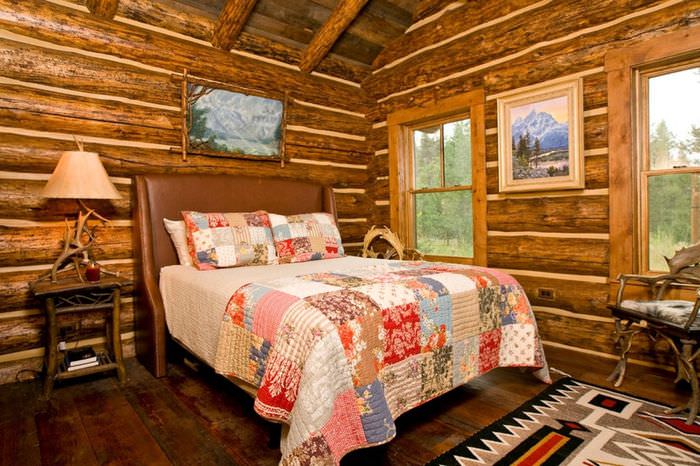 غطاء سرير متنوع من قصاصات من القماش على سرير في منزل خشبي