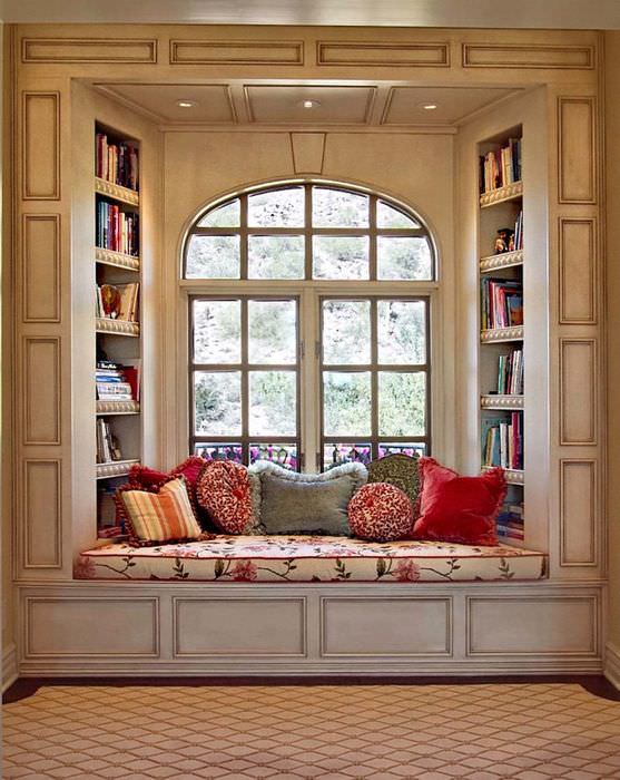 Малък диван за четене на книги в отвора на прозореца