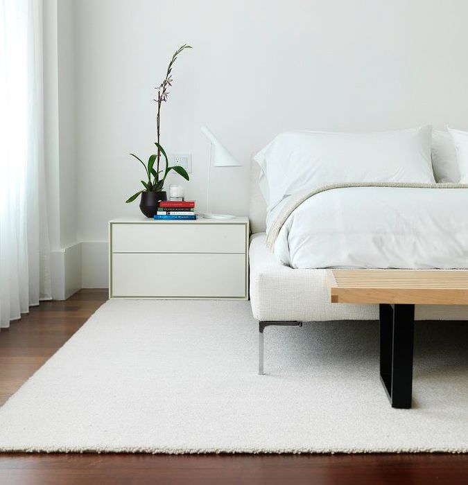 Minimalistisk hvidt tæppe på soveværelsesgulvet