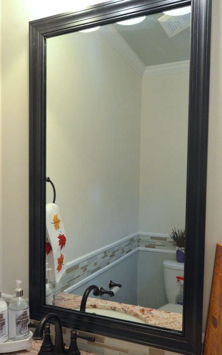 Černý rámeček ze soklu na zrcadle v koupelně