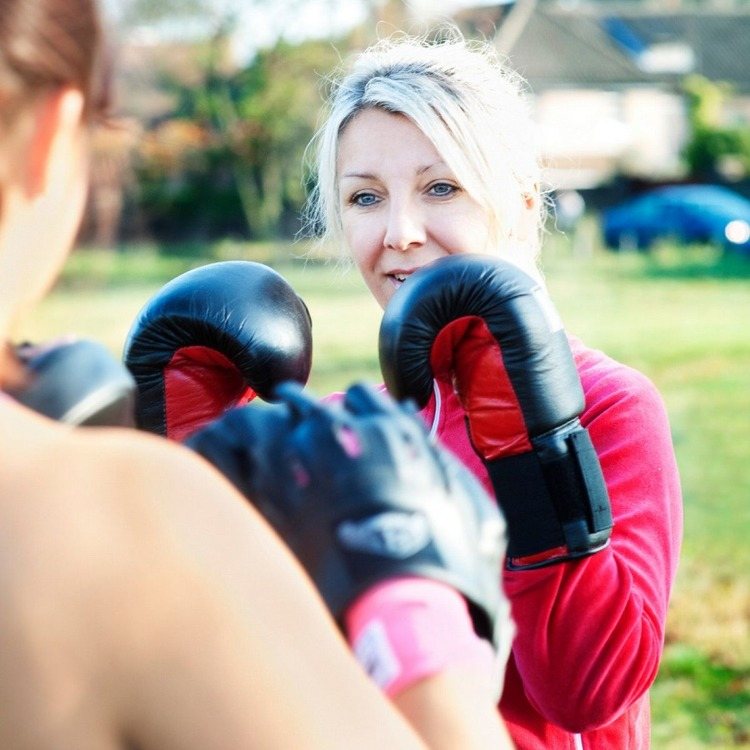 motiveret kvinde, der forbrænder kalorier, mens hun træner til kickboksning eller boksning