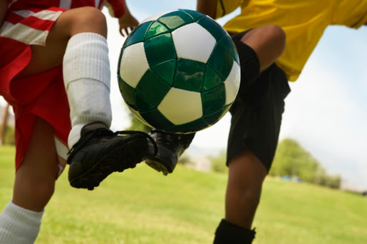 Unge fodboldspillere på fodboldbanen duellerer om bolden