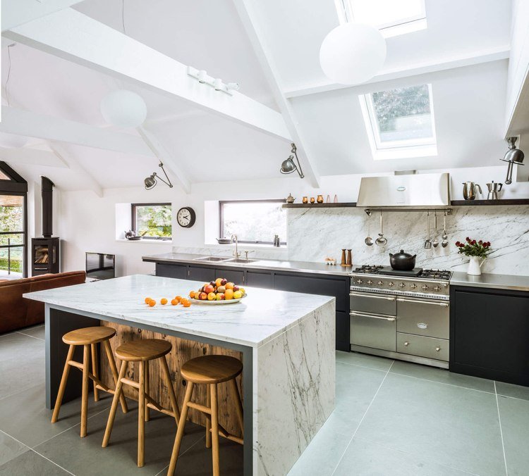 Moderne køkken under et skråt loft med køkkenø med lille bord uden apparater af træ og marmor