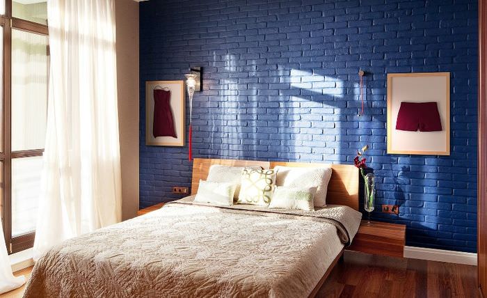 Kétszemélyes ágy egy kék téglafalú szobában