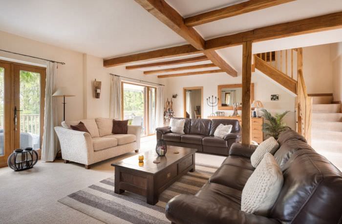 Dřevěné trámy na stropě obývacího pokoje s hnědou sedačkou