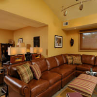 Ruskea sohva keltaisten seinien taustalla
