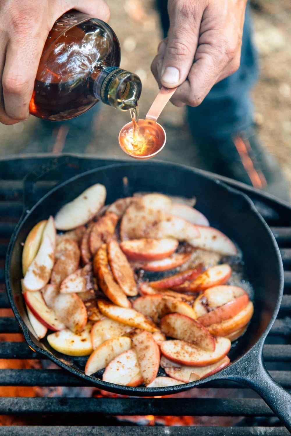 Læg æbler med måleske med kanel og bourbon whisky over støbejernspande