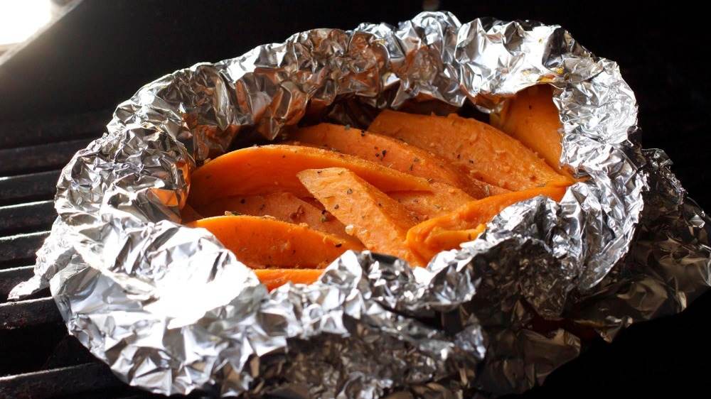 Pak de krydrede søde kartofler ind i aluminiumsfolie og lad dem bage i gløderne