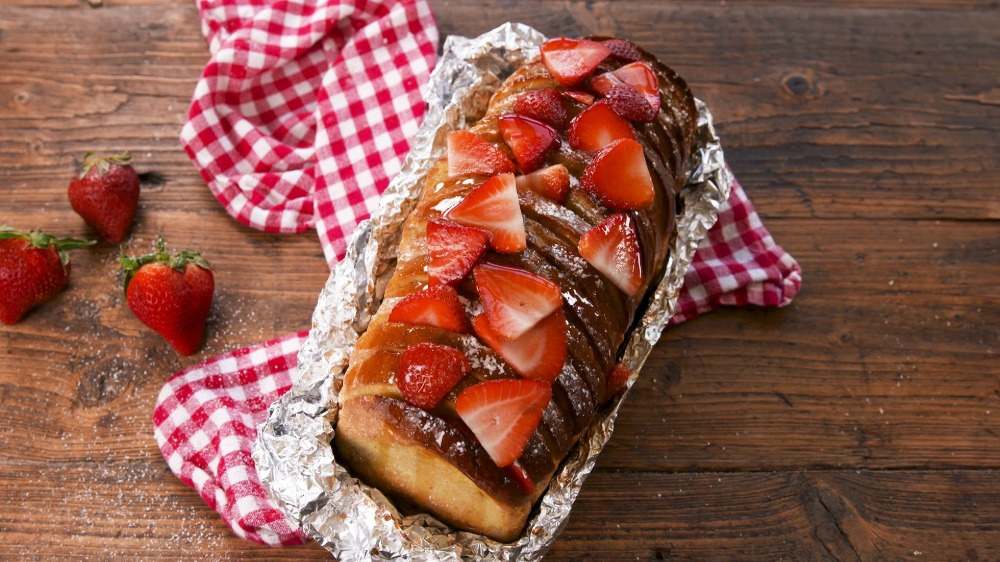 Smagfuldt sødt brød med jordbær indpakket i aluminiumsfolie til camping madlavning dessert eller morgenmad
