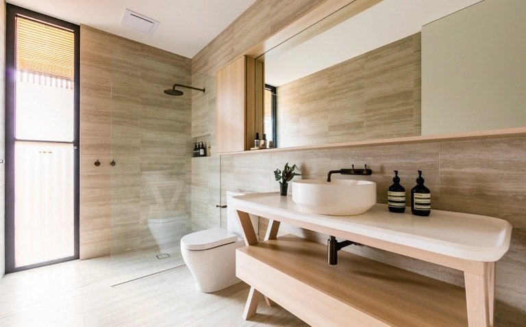 Moderne badeværelser med brusekabine og naturstenfliser på væggen, regnbruser og håndvask i træ med håndvask