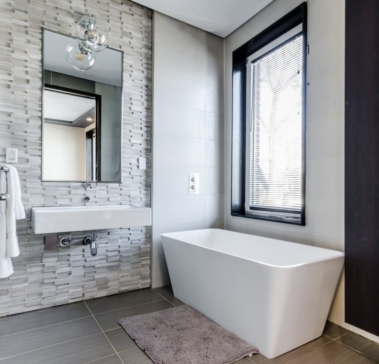 Moderne badeværelser i gråt med vægge beklædt med natursten med et fritstående badekar uden bundenhed