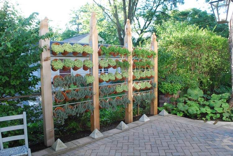moderne-privatlivsbeskyttelse-have-træ-stolper-ler-krukker-planter-havedesign
