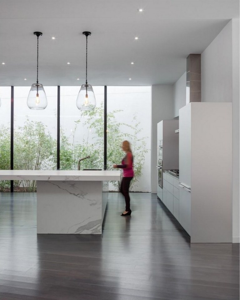 moderne hvidt køkken med håndtagsløse køkkenskabe og ø med bordplade i marmor