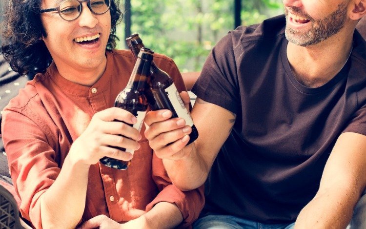 to smilende venner, der drikker øl, der støder på ølflasker