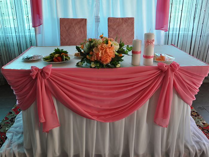 Ein Rock aus rosa Tüll auf der Hochzeitstafel des Brautpaares